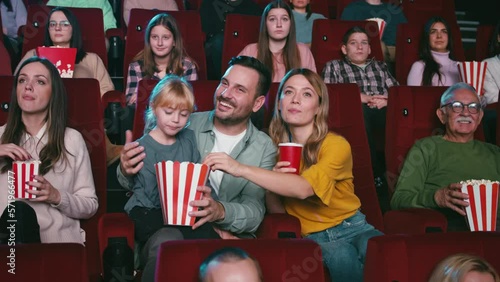 Cheerful family watching movie in theater.