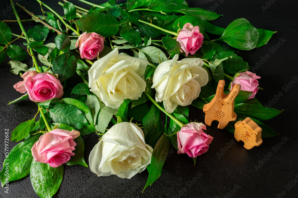Fototapeta premium White and pink roses in drops of water. Nearby are wooden toys. Image for postcard, announcement, event, memorial day