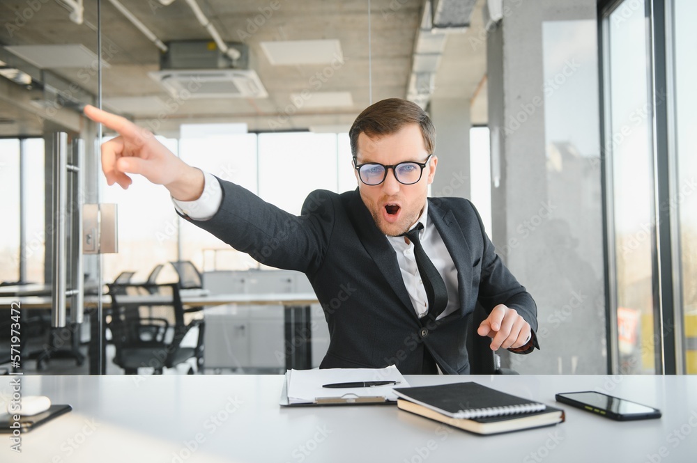 Angry businessman sitting at his desk and screaming at his employees. Angry businessman sitting at his desk and screaming at his employees.