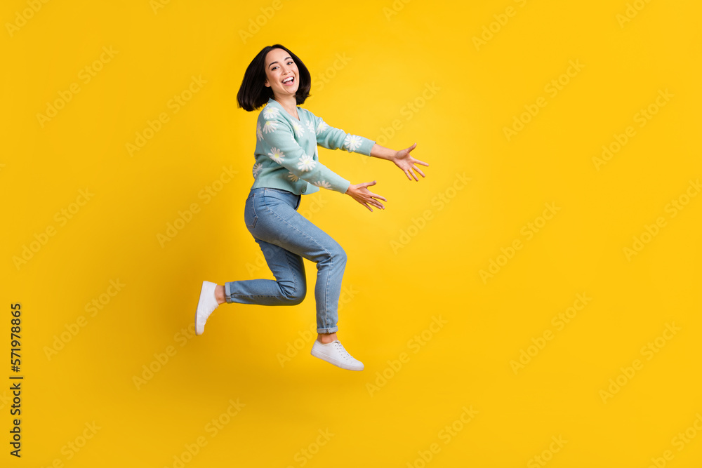 Full size photo of good mood woman bob hairstyle dressed blue pullover running hold empty space isolated on yellow color background