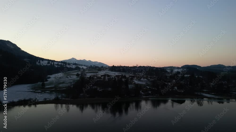 the Weißensee in the south of Bavaria with a small town at the lake covered with snow in the background filmed during the sunset with a drone and the lake in the foreground the Weißensee in the south of Bavaria with a small town at the lake covered with snow in the background filmed during the sunset with a drone and the lake in the foreground