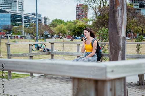 young woman outdoors sitting sending a voice note photo