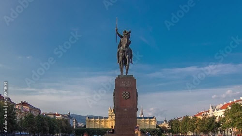 Monument of the Croatian King Tomislav timelapse hyperlapse and art pavilion in colorful park, in Zagreb, capital of Croatia. Blue cloudy sky before sunset. Panoramic view photo