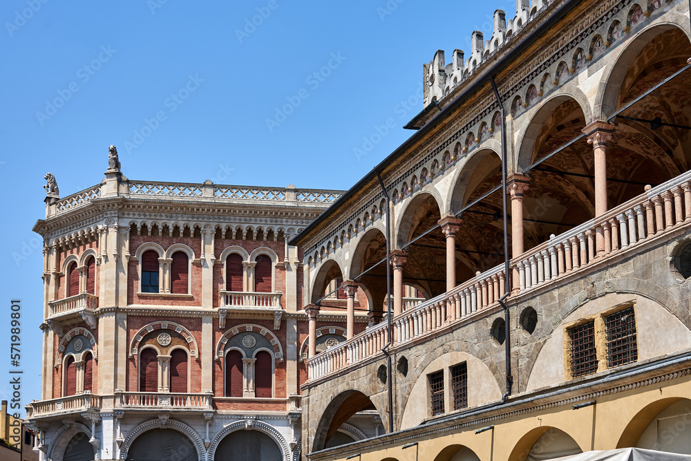 Fragment of the colonnade of the medieval Palazzo della Ragione market hall against the background of the facade of a historic tenement house in the city of Padua