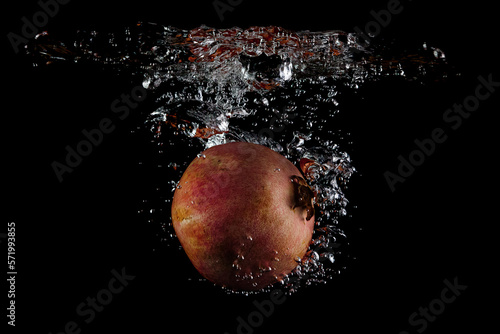 Pomegranate water splash on black background
