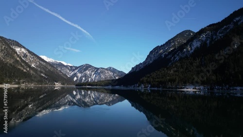 the plansee in the mountains with slightly snowy mountains and bright sunshine in austria near the city of reutte taken in winter