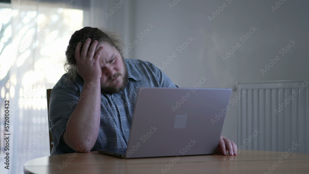 One sad man feeling despair in front of laptop computer. Unhappy emotion of a male fat person not liking result online feeling frstration One sad man feeling despair in front of laptop computer. Unhappy emotion of a male fat person not liking result online feeling frstration