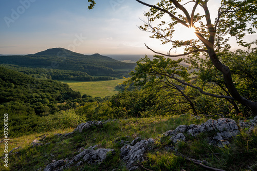 view of hill meadows and Spiš Castle in the Slovak Little Carpathian Mountains with the setting sun in the background photo