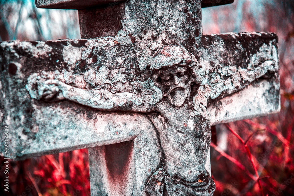Old stone statue of Jesus crucified on the cross on the tombstone in the cemetery in Ukraine