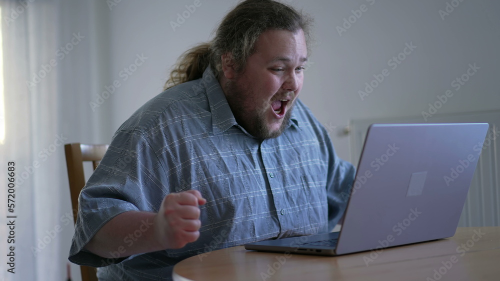 One excited chubby guy celebrating success in front of laptop computer. male person dancing in happiness. WOW emotion One excited chubby guy celebrating success in front of laptop computer. male person dancing in happiness. WOW emotion
