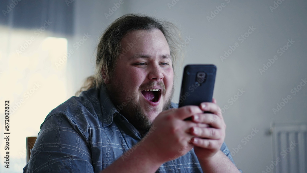 Joyful guy holding phone liking content online. Happy emotion of male casual person feeling excitement Joyful guy holding phone liking content online. Happy emotion of male casual person feeling excitement