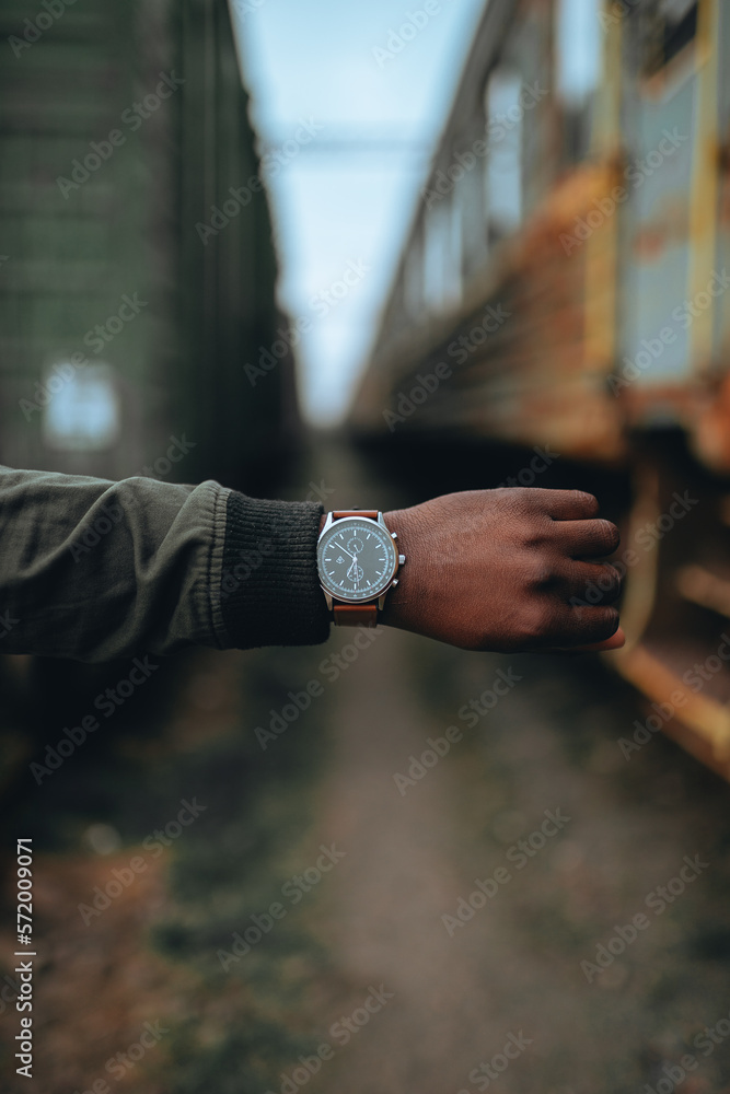 Close-up of a watch with a brown leather strap on an African American hand. Blurred background. Isolated object on bokeh background