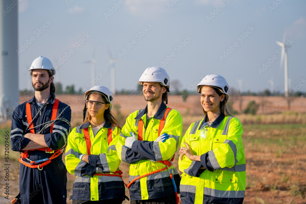 Fototapeta premium Group of engineer or technician workers stand in a row with arm-crossed and look to right side also smiling and stand in front of windmill cluster.