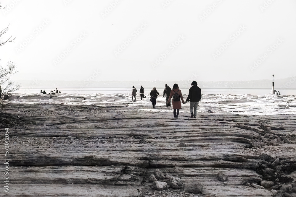 Dreamy Nostalgia: People Walking on Rocky Shoreline in Black and White