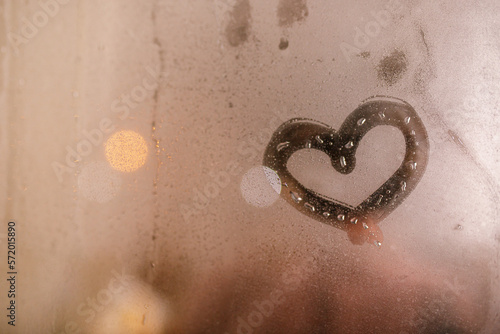 A heart painted on a misted window. Heart on misted glass. Heart on a window background. Heart symbol of love drawn on the glass