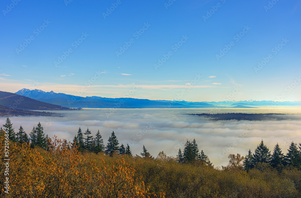 Dense cloud inversion over valley floor during Fall, with mountains in silhouette on far horizon.