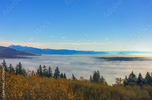 Dense cloud inversion over valley floor during Fall  with mountains in silhouette on far horizon.