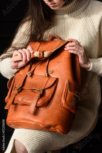 photo of a woman with a orange leather backpack with antique and retro look. indoors photo