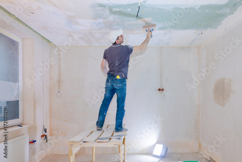 Worker make repairs in new apartment. Man plaster walls and ceilings. High quality photo