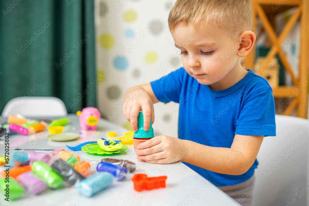 Cute children sitting at the table and plays with playdough Cute children sitting at the table and plays with playdough