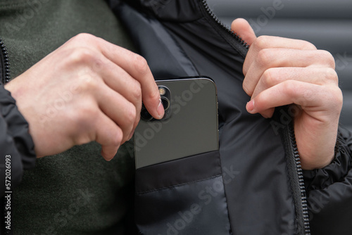 Papier peint The man puts the phone in the inner pocket of his black jacket