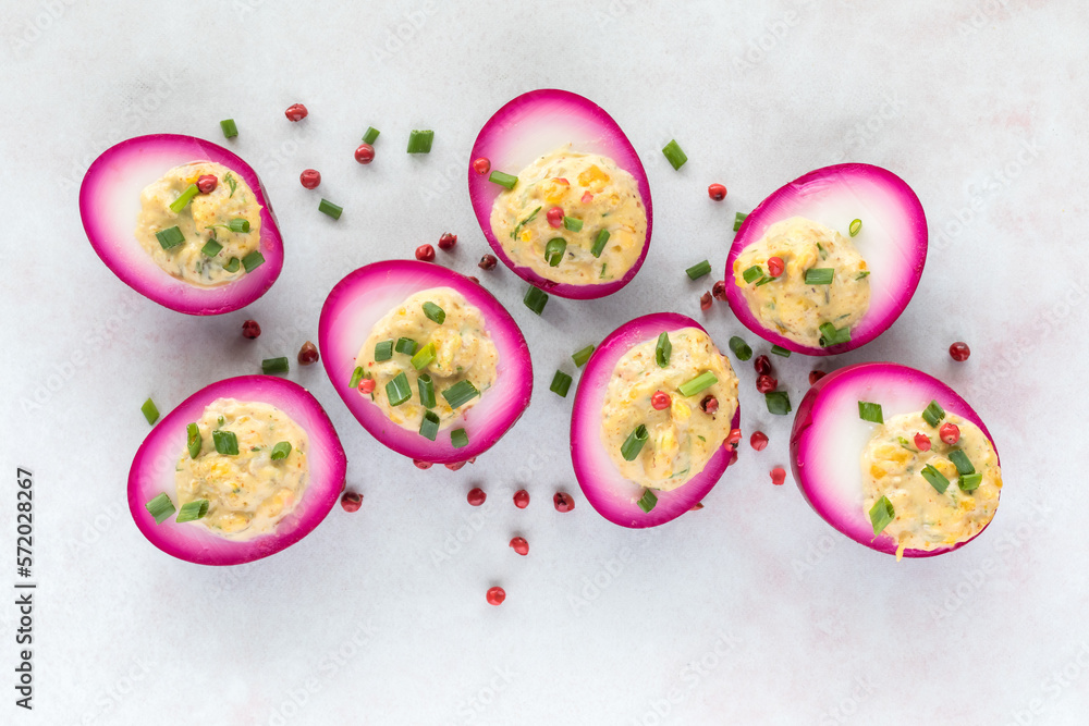 Bright beet juice soaked Deviled eggs garnished with chives and peppercorns.