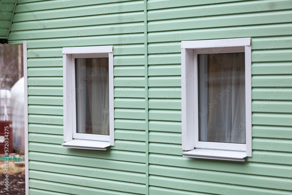 Two plastic windows on the facade of the house. siding finish