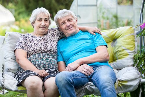 Elderly married couple sitting in a hanging garden bench at the courtyard