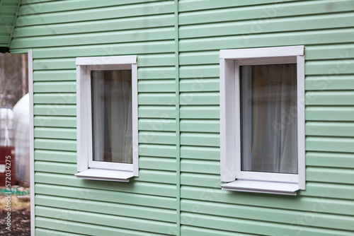 Two plastic windows on the facade of the house. siding finish