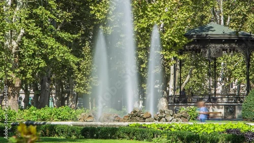 Fountains in Zrinjevac, one of the oldest parks in city timelapse. Zagreb, Croatia. People sitting around and making photos photo