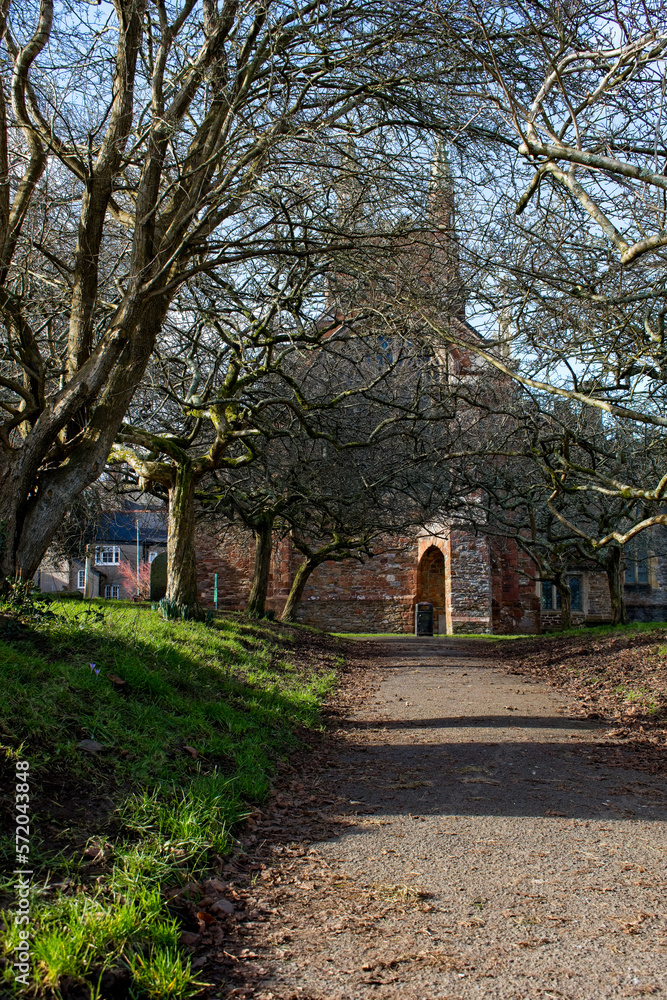 Pretty Red stone church of St Mary in a Devon town. Capture shows the path leading to the doors in wintertime. 
