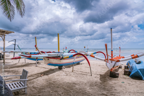 Traditional Balinese boats in different colors on Sanur beach in Bali, Indonesia. Sea side at background