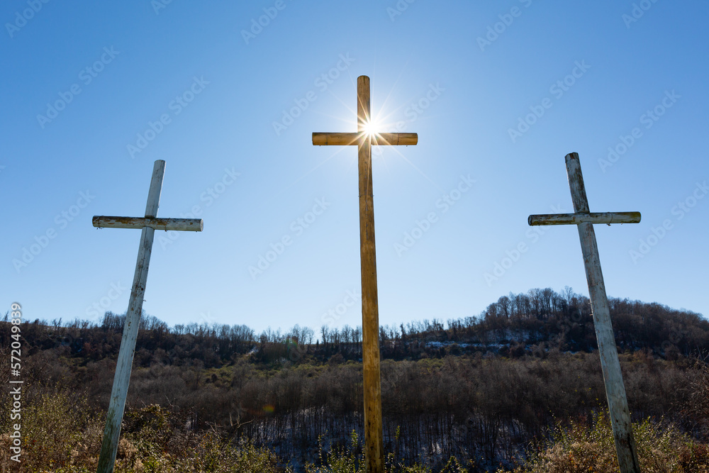 Sunlight on three wooden crosses on hill