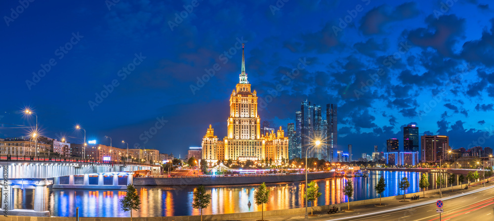 Illuminated high-rise stalinist building near river at summer night in Moscow, Russia. Historic name is Hotel Ukraina.