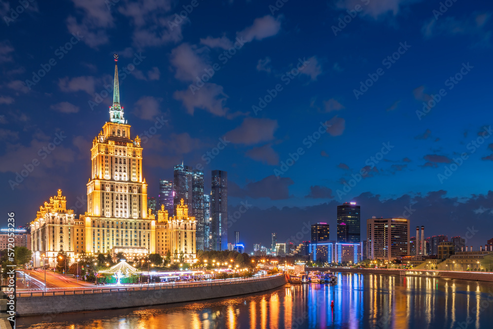 Illuminated high-rise stalinist building near river at summer night in Moscow, Russia. Historic name is Hotel Ukraina.