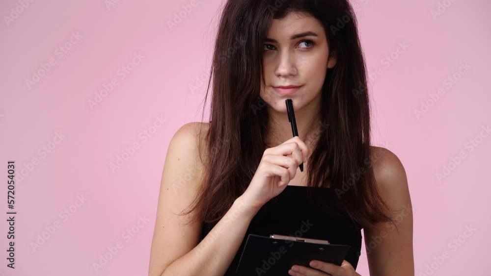 4k video of one girl which thinks and notes something with a pen on tablet over pink background. 4k video of one girl which thinks and notes something with a pen on tablet over pink background.