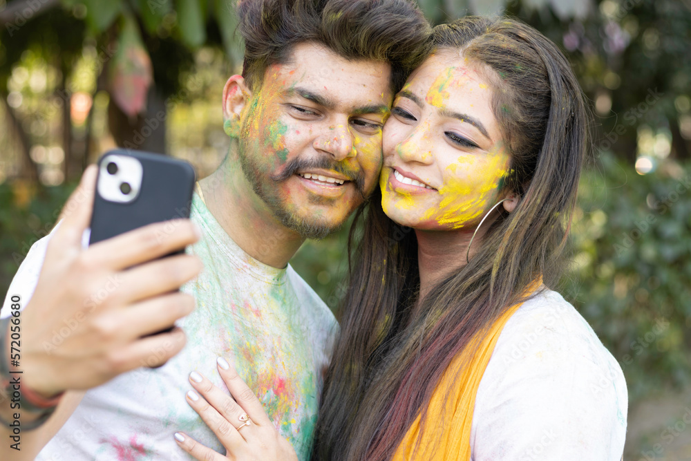 Two young girls sisters friends family taking photo selfie enjoying holi festival of colors colours outdoor in a park a popular hindu festival celebrated across india with gulal abeer color powder Two young girls sisters friends family taking photo selfie enjoying holi festival of colors colours outdoor in a park a popular hindu festival celebrated across india with gulal abeer color powder