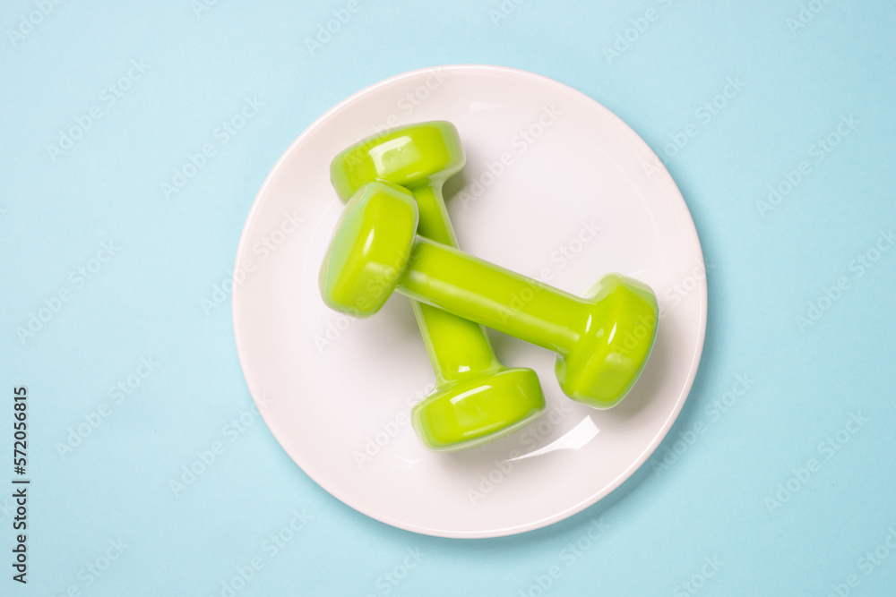 Healthy lifestile, fitness, diet and weight loss concept. Dumbbells at white plate. Healthy lifestile, fitness, diet and weight loss concept. Dumbbells at white plate.