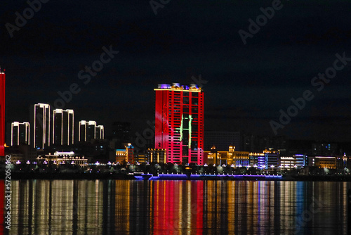 View of the Chinese city at night. Neon illumination of houses on the Amur River.