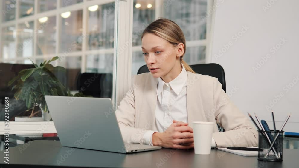 Serious business woman talking on video conference online in office. Pretty worker having video call on laptop computer indoor. Female professional explaining project talking to web cam at workplace. Serious business woman talking on video conference online in office. Pretty worker having video call on laptop computer indoor. Female professional explaining project talking to web cam at workplace.