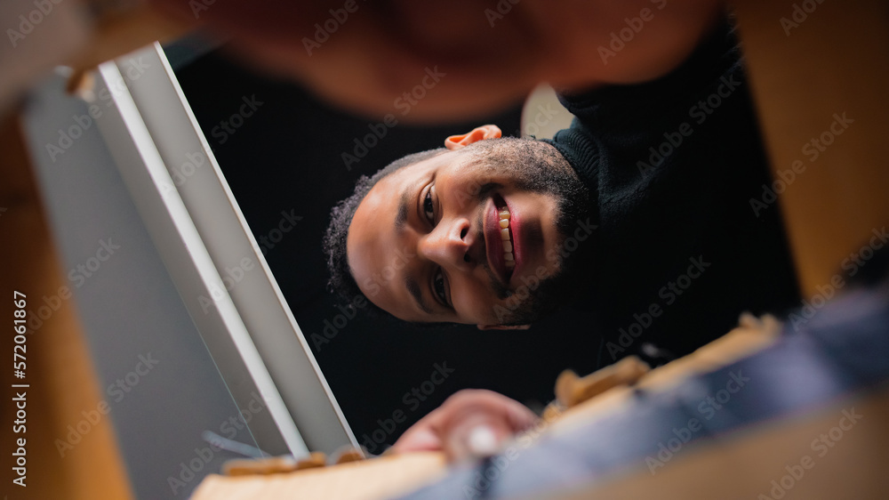 Obraz premium latin man opening cardboard box. Happy man opening gift.