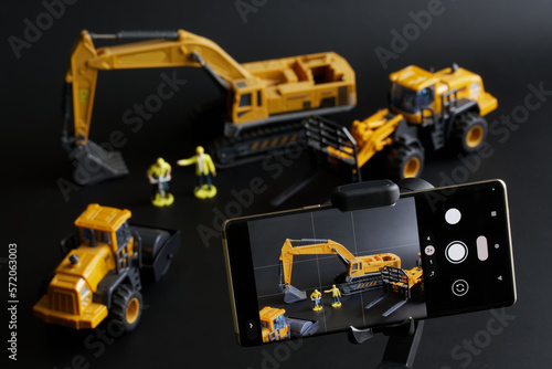 Modern smartphone on gimbal selfie stick for photo-video  filming toy construction machinery and workers. Construction inspection and supervision. Concept of live broadcasting  streaming  journalism