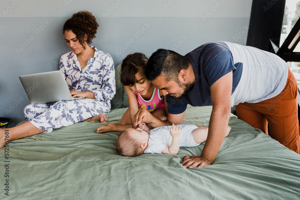 Happy hispanic family laughing and having fun together on the bed at home in Mexico Latin America Happy hispanic family laughing and having fun together on the bed at home in Mexico Latin America