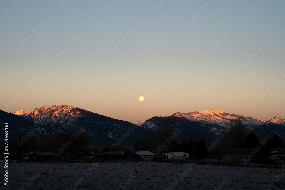 Sunrise and Moonset over the Bitterroot Mountain in Montana with Alpen Glow and Snow