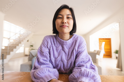 Happy asian woman sitting at table and having video call