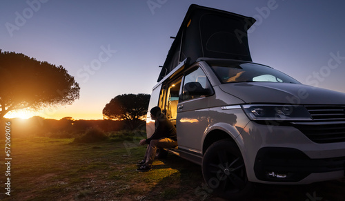 Obraz na płótnie man sitting with digital device at his Transporter Camping Van bus at the California Ocean in the coastal Nature - digital nomades concept w salonie