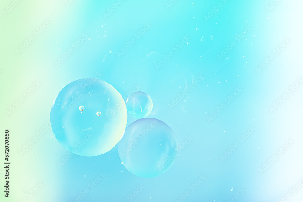 Gradient background in white and sky soft tones. Macro drops of oil on the surface of the water. Delicate cosmetic background for advertising products.