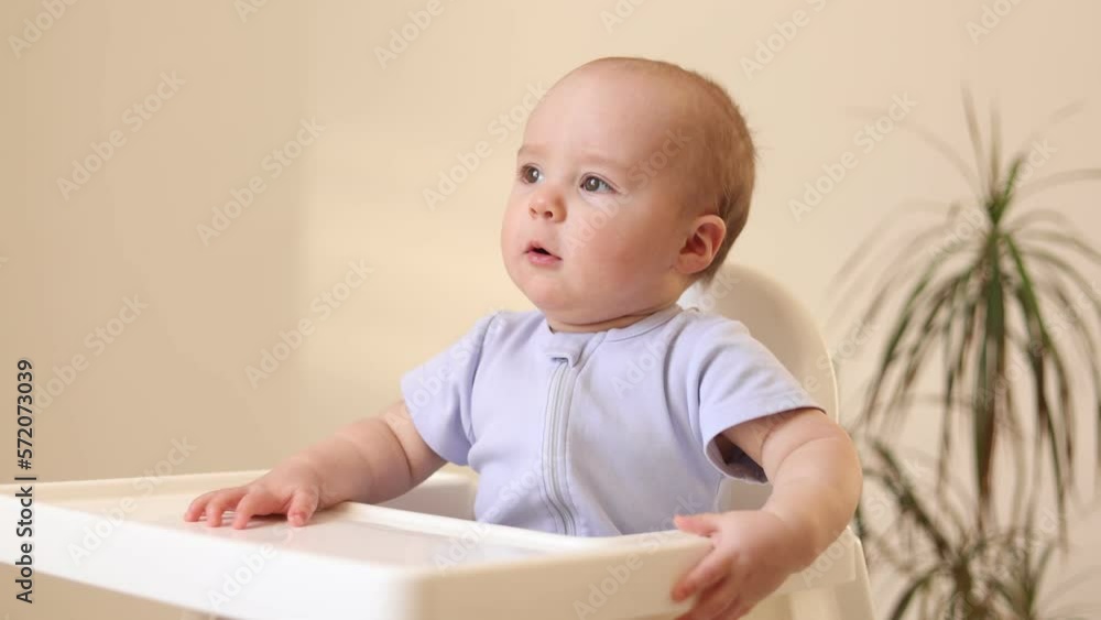 a cute kid in a yellow bodysuit is sitting in the kitchen with cans of baby food. The first complementary feeding of the child. Baby purees. High quality photo