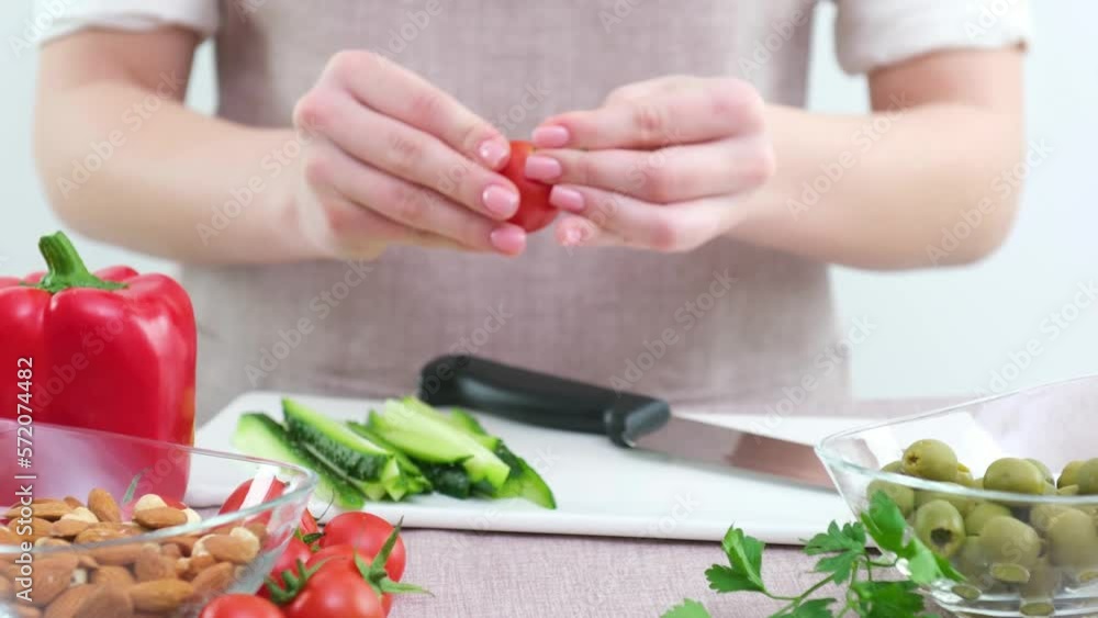 close-up on the table glass plate with nuts almonds tomatoes and bell peppers on background female hands cut cucumber healthy vegetarian food close-up on the table glass plate with nuts almonds tomatoes and bell peppers on background female hands cut cucumber healthy vegetarian food