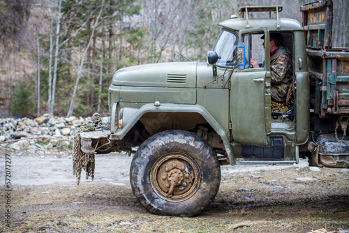 An old military truck in the swamp of green color with metal chains